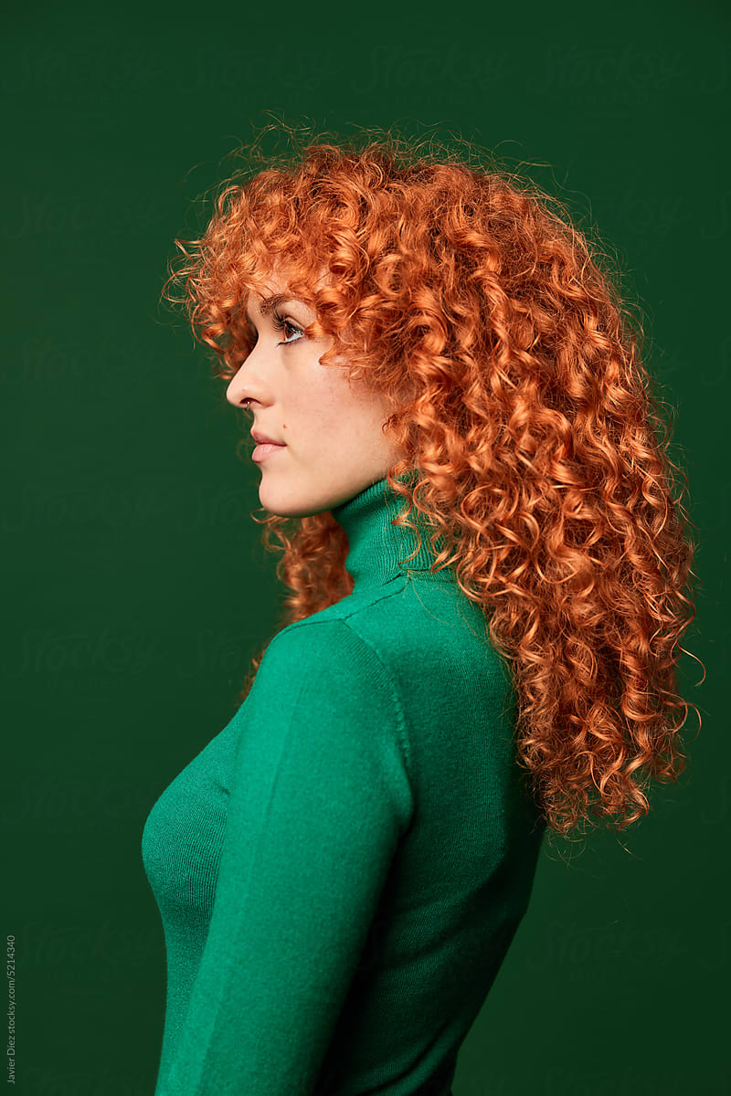Profile of young ginger woman on green background