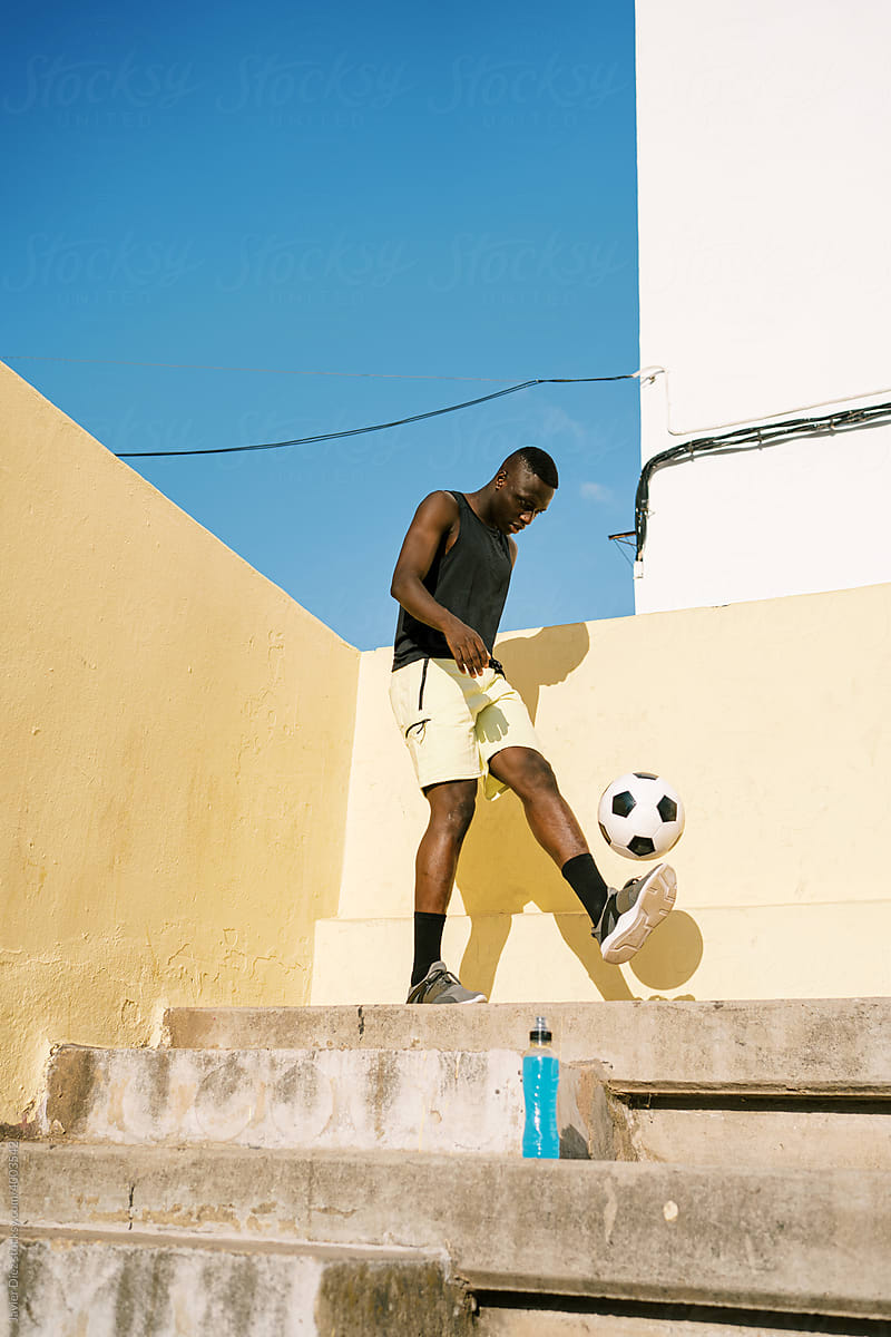 Black sportsman bouncing football ball