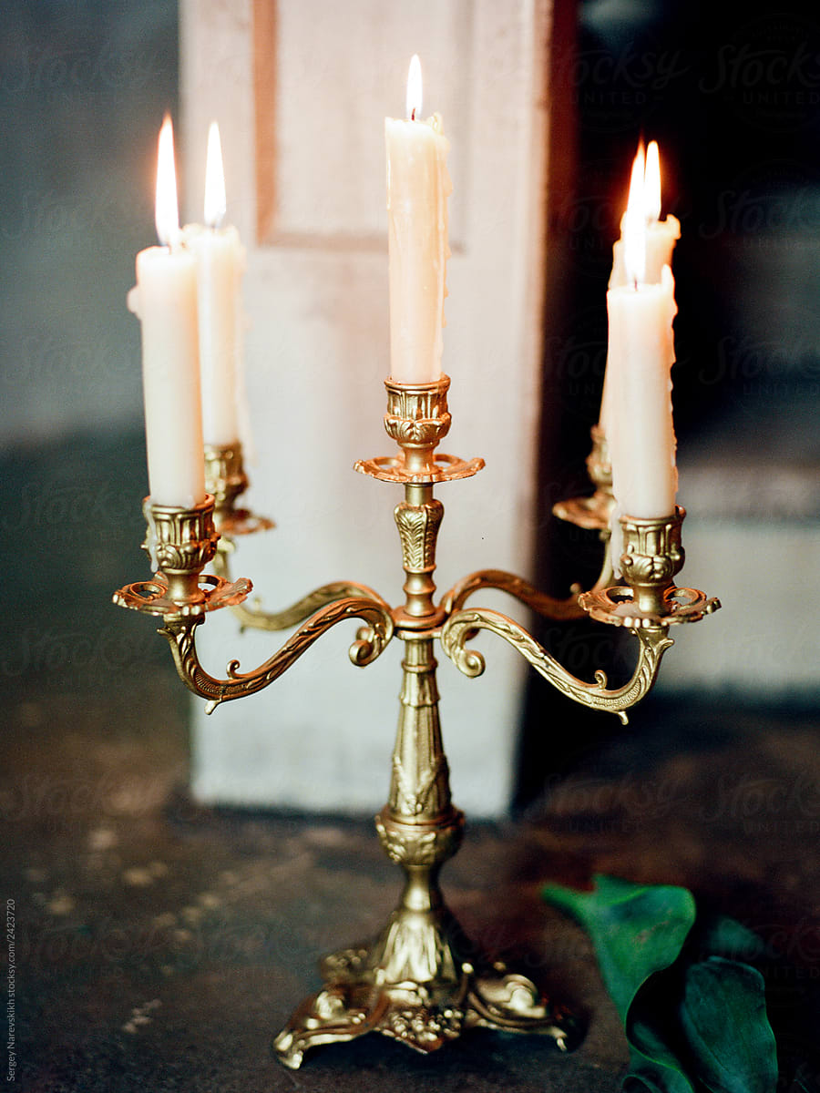 Candlestick with burning candles standing on floor near stairs