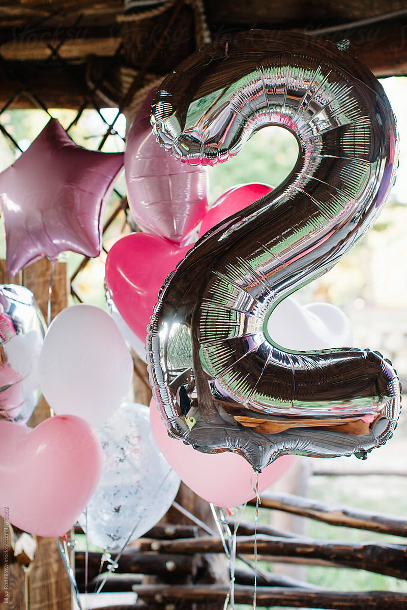 Silver ballon in shape of number two among pink balloons