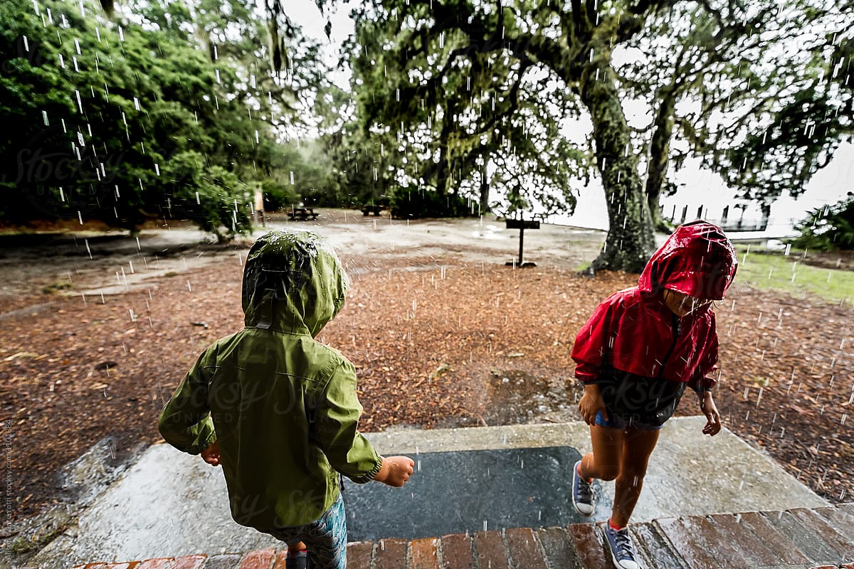 Two Children Playing In The Rain In A Storm