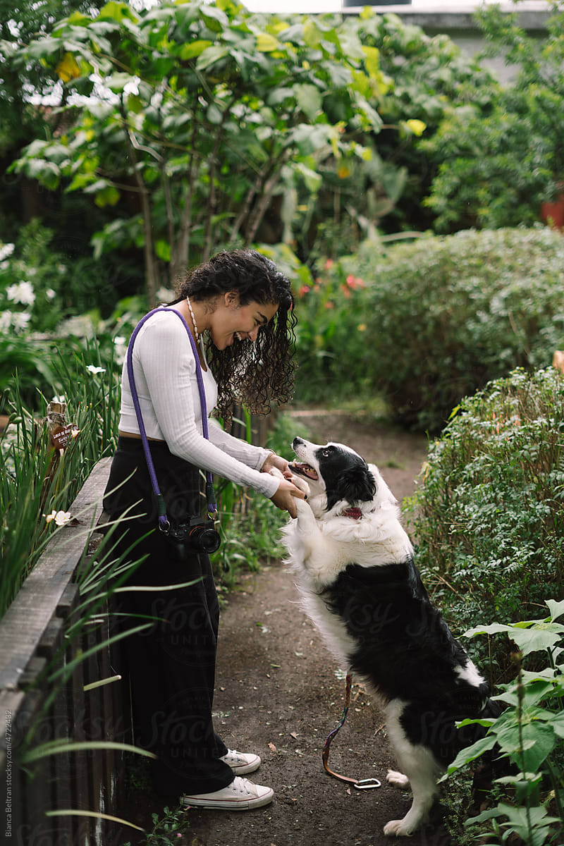 Young Latina woman enjoying the companionship of her dog in a garden.
