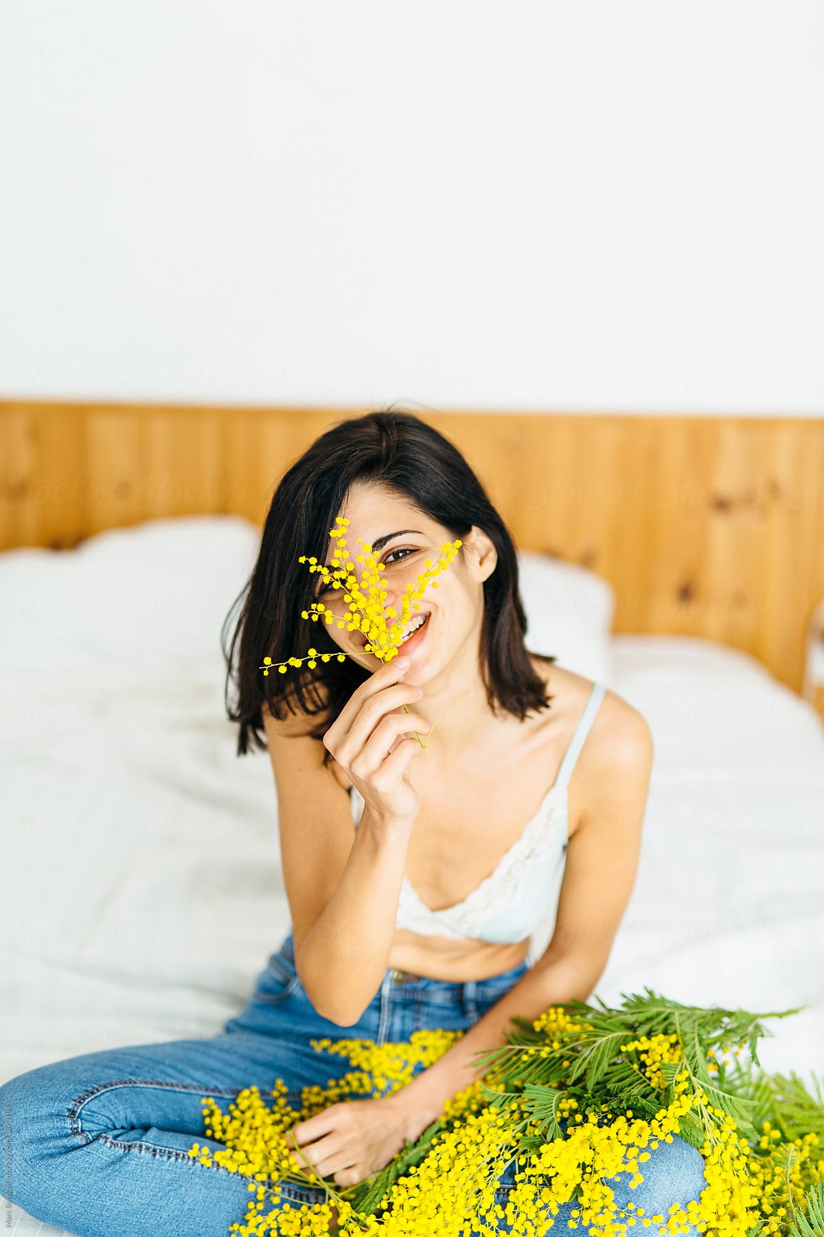 happy brunette girl covering her face with mimosa plants