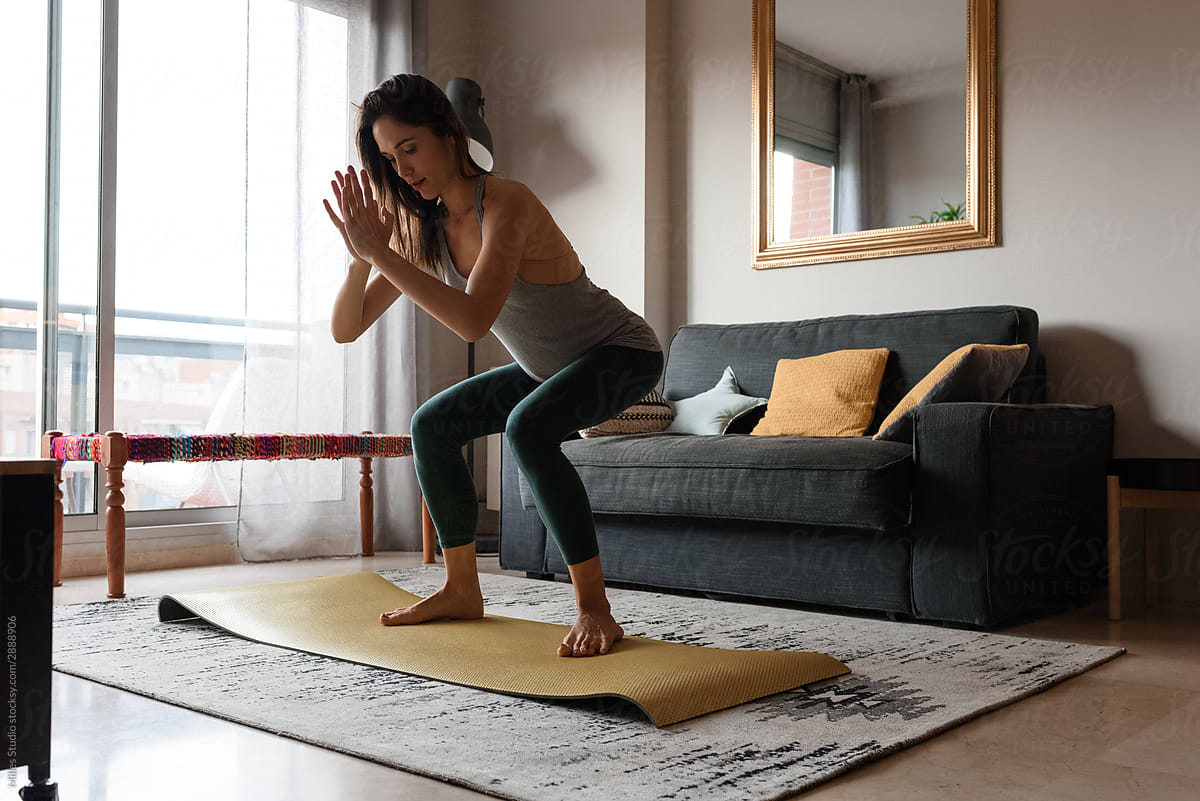 Slim woman doing yoga in living room