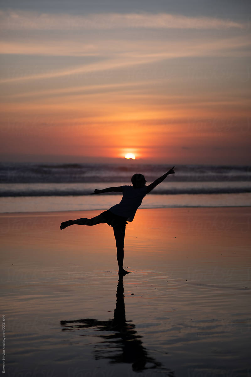 Silhouette of a woman exercising on a beach at sunset
