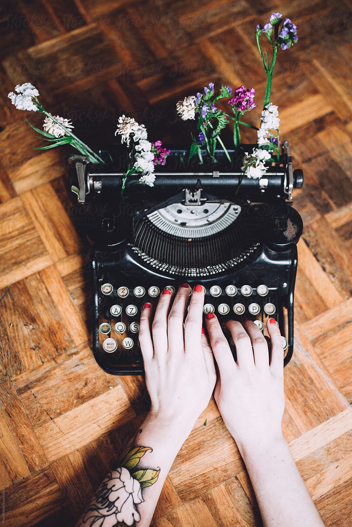 Woman typing with a vintage typewriter with flowers
