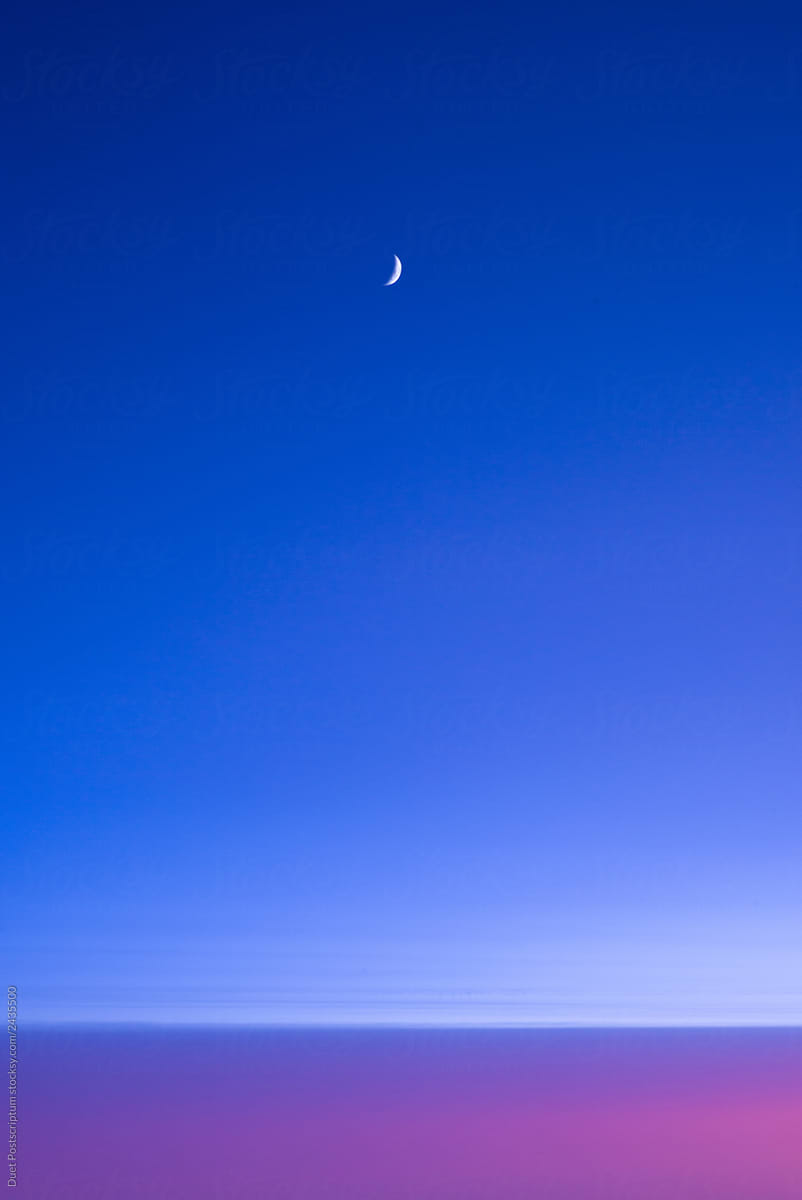 Moon in blue sky above purple horizon