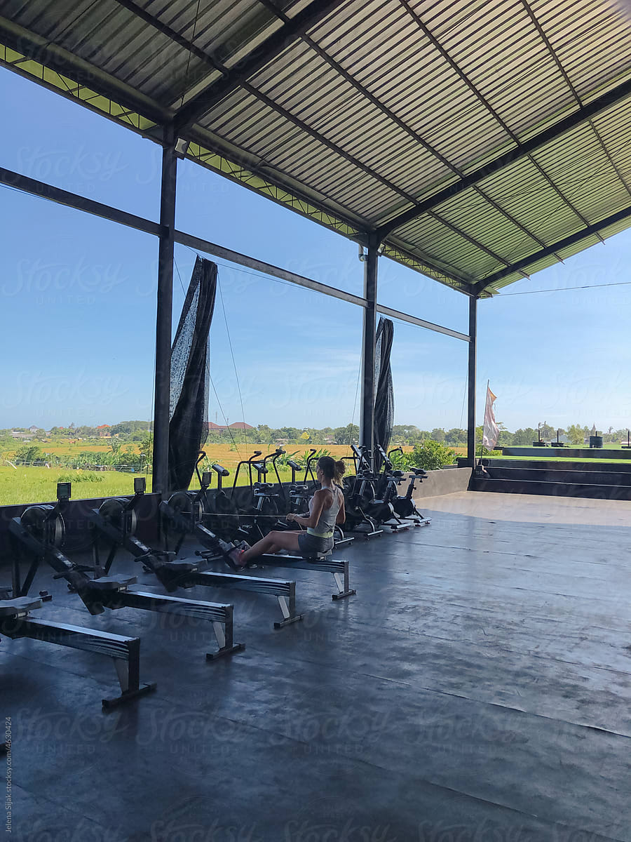 UGC, Woman working out, doing machine rows in an open gym, Bali