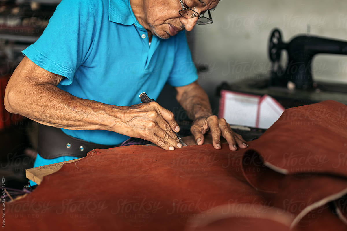 Hispanic senior shoemaker working the leather