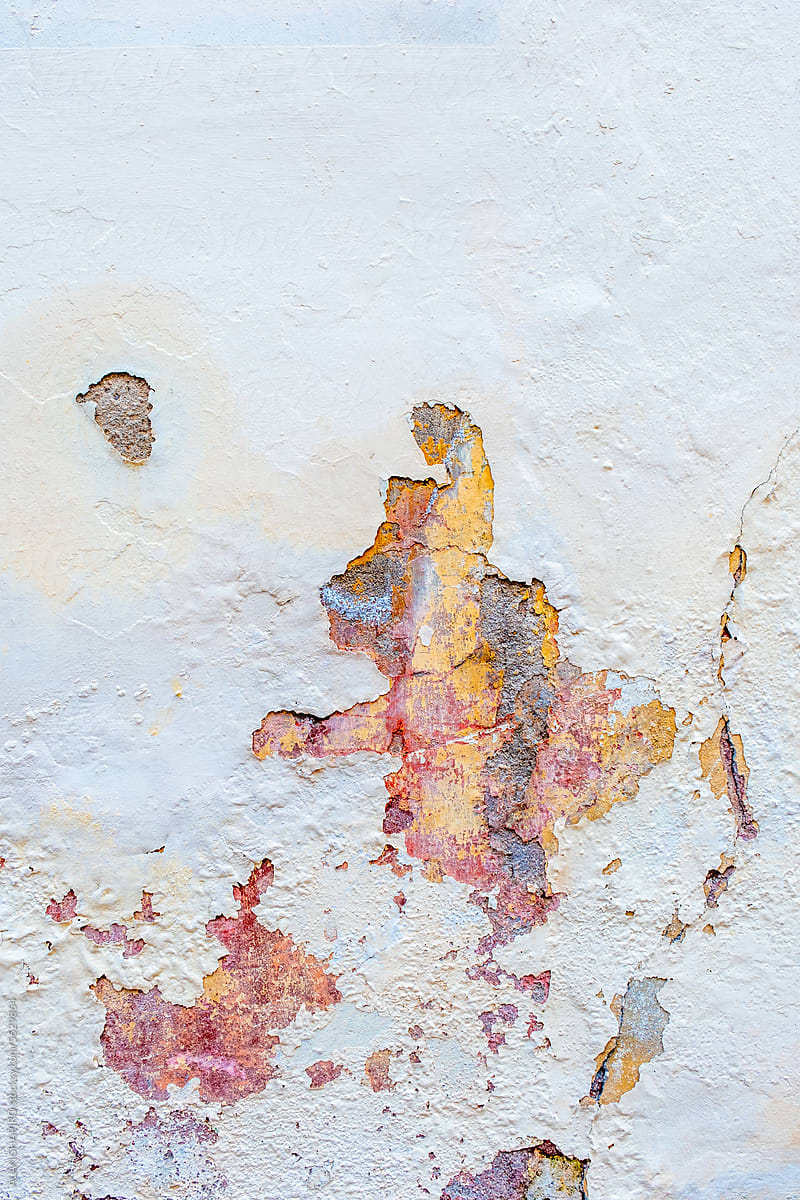 painted, old white wall with colorful holes showing through