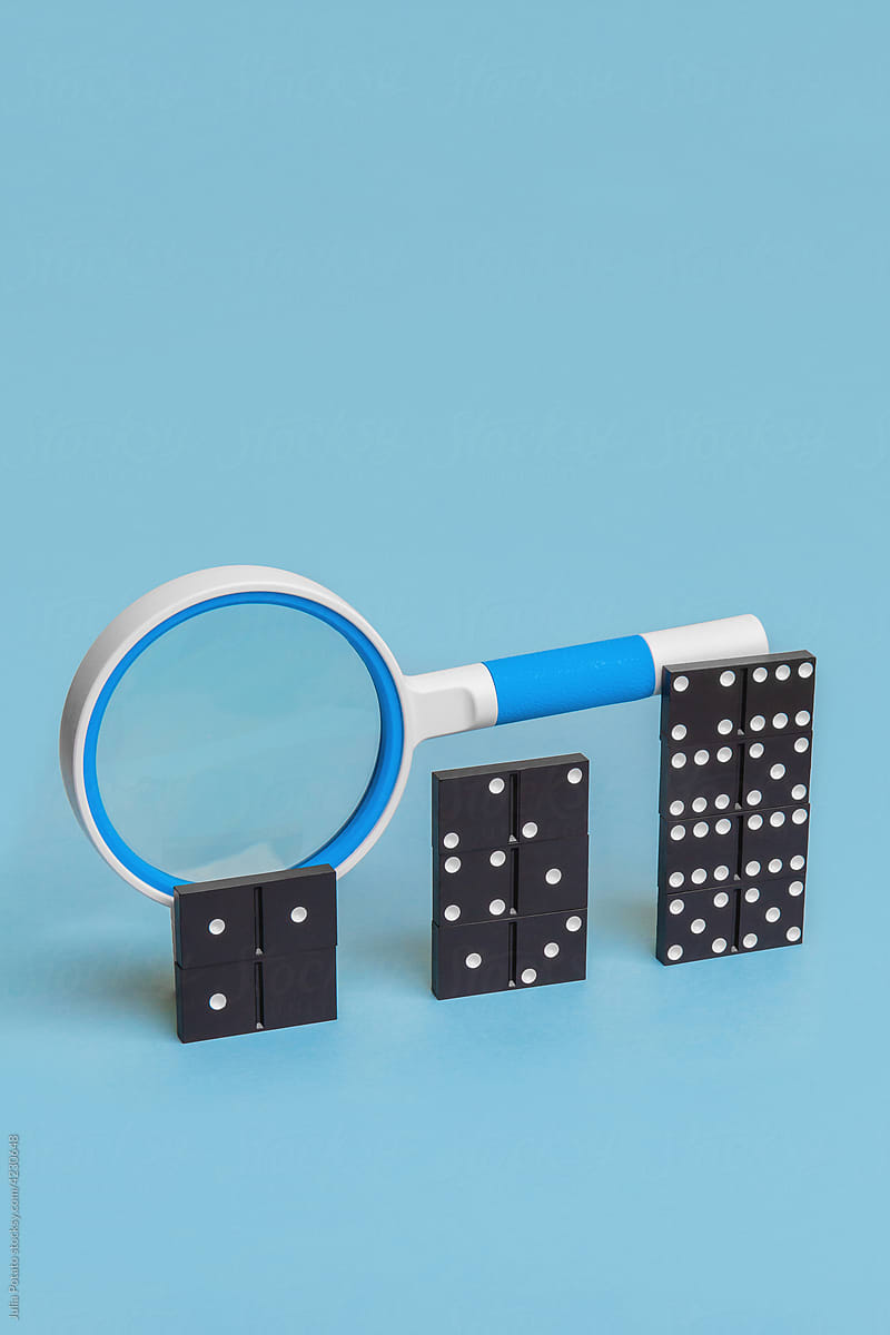 A magnifying glass lying on columns of dominoes