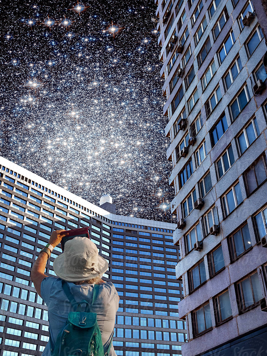 Surrealistic collage. A man shoots on camera the starry sky in the city