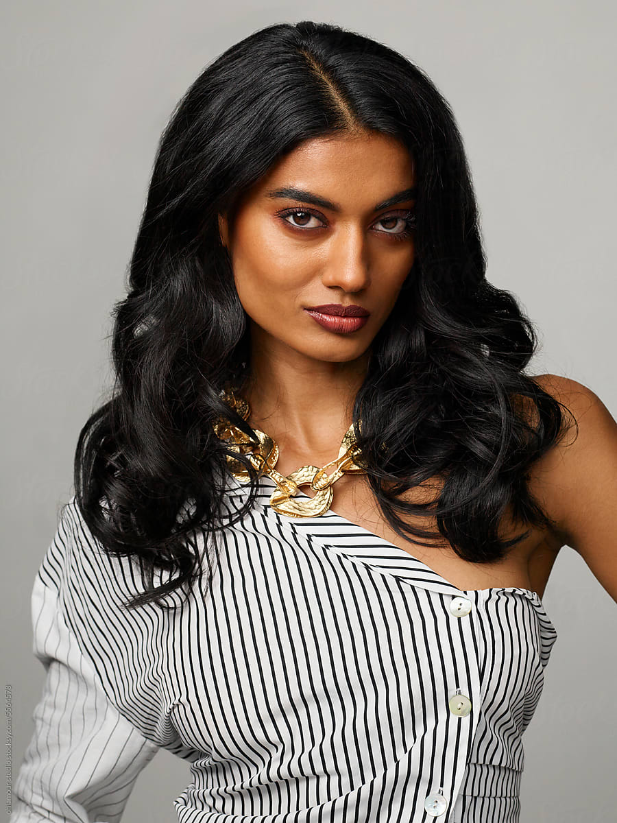 Confident woman wearing bold one shoulder blouse and jewelry portrait