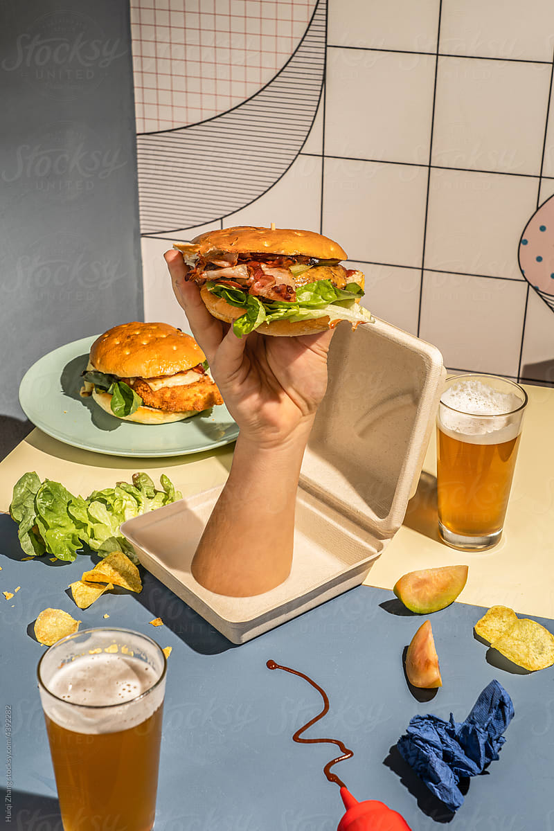 A hand holding a hamburger at the table