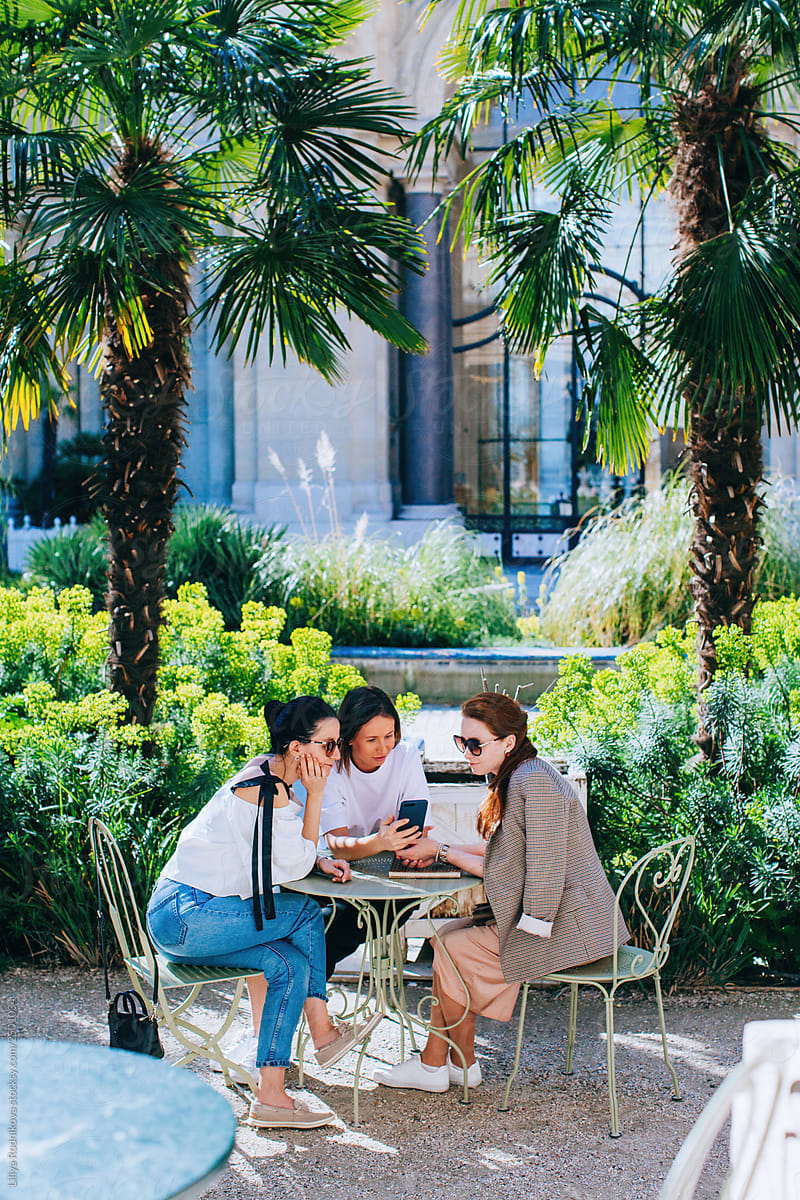 Three friends sitting at the table at the garden and chatting