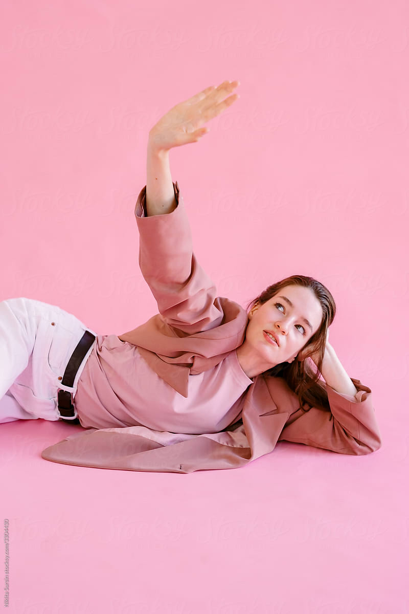 Girl posing lying in studio on pink background