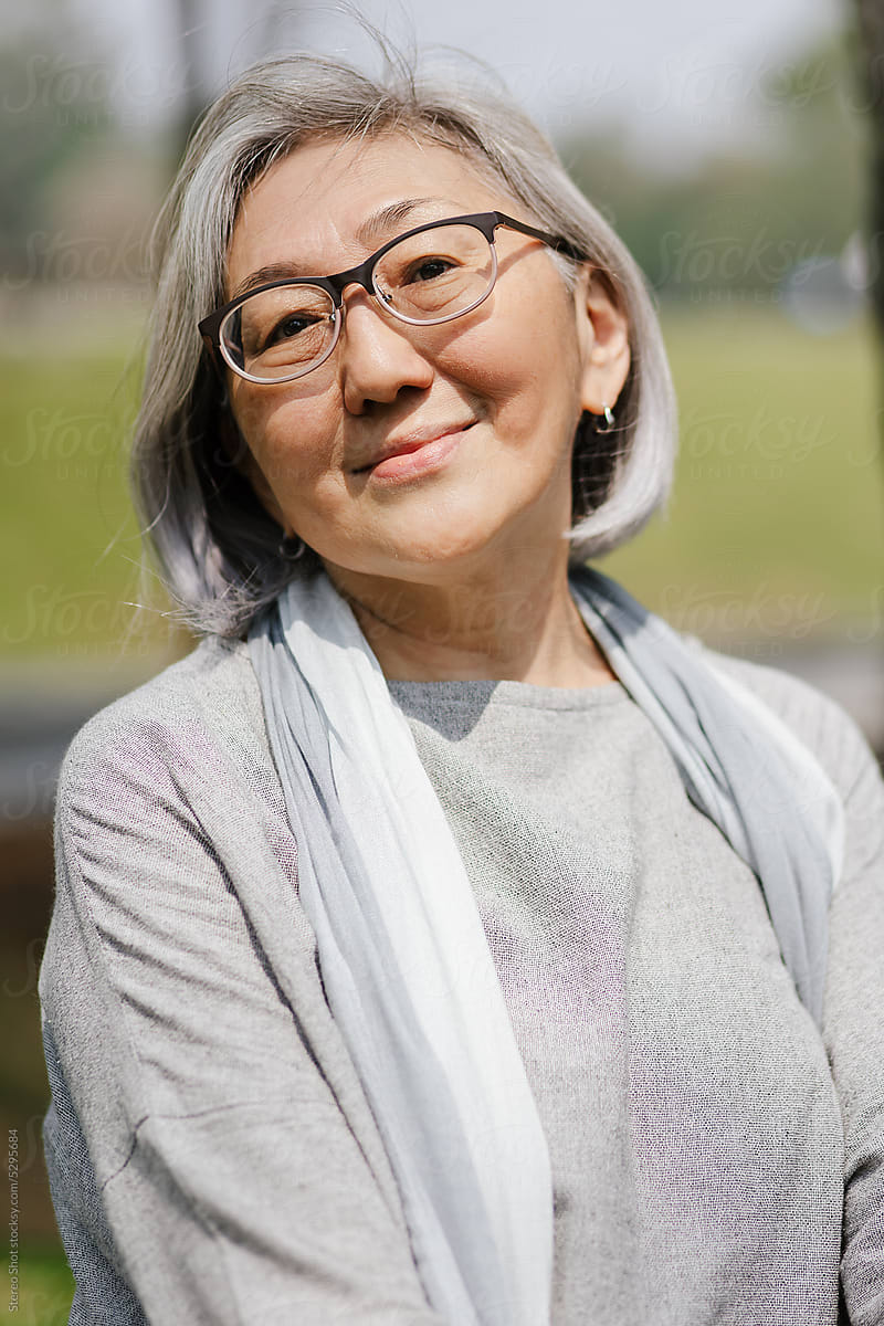 Satisfied elderly Asian woman in park