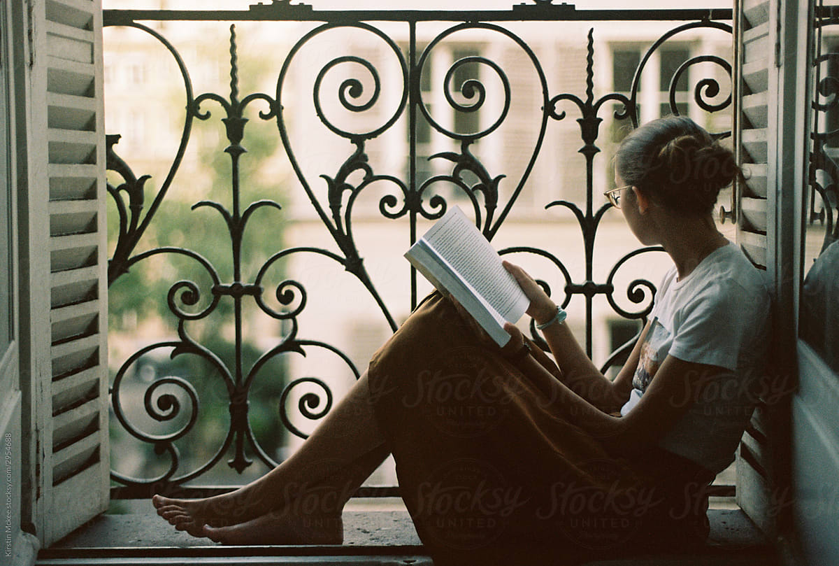 Girl reading book with view from balcony in Paris