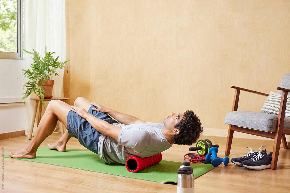Athletic man doing abs exercise with foam roller