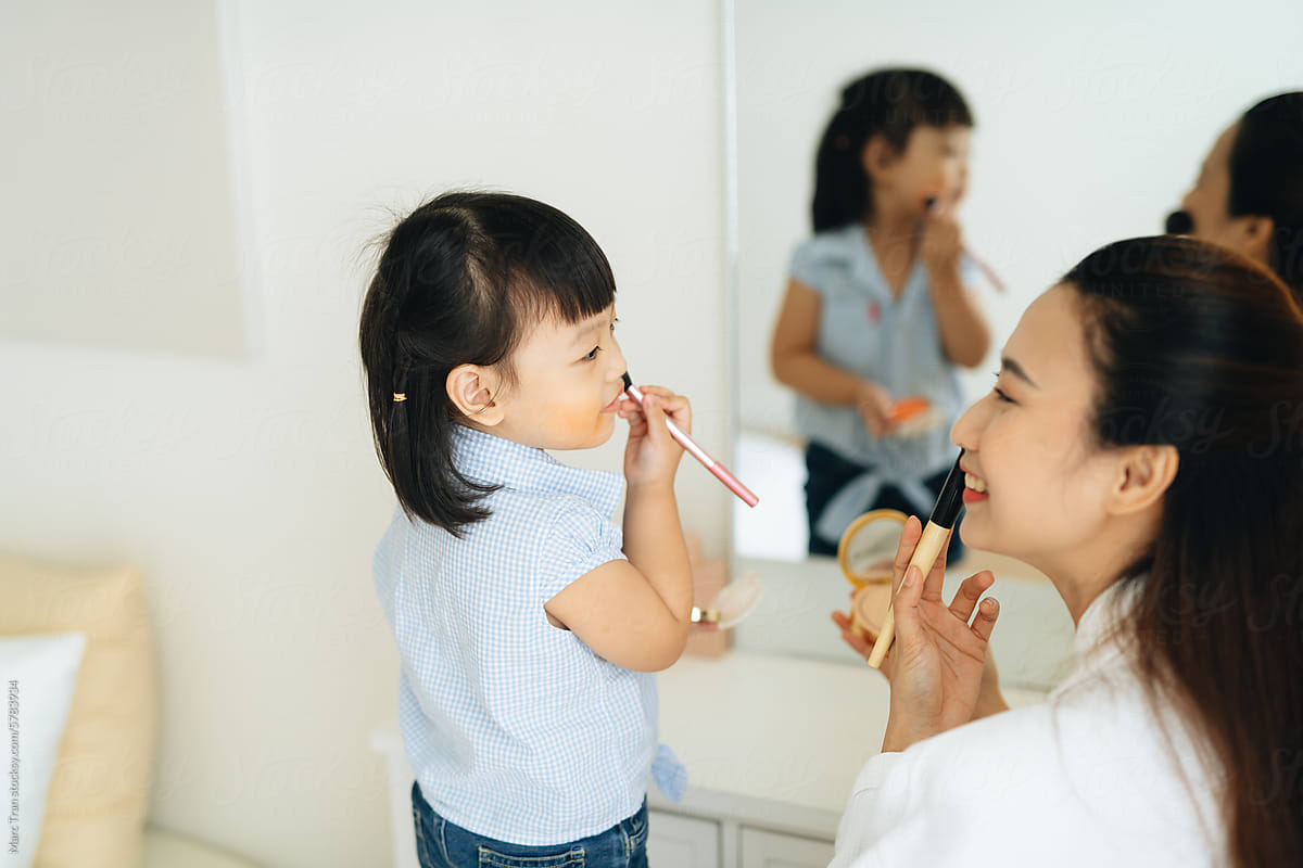 A beautiful young mother is trying to do makeup with her daughter