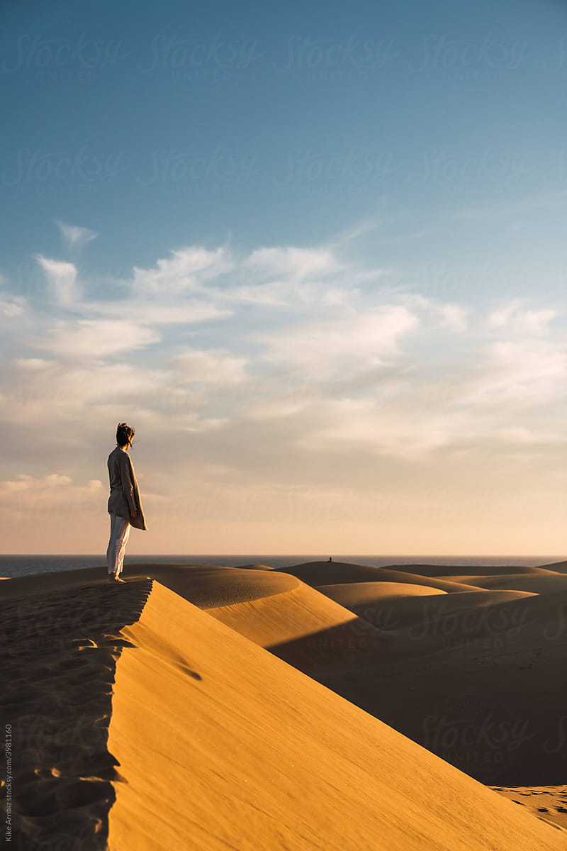 Woman standing on sand land and blue sky at sunset