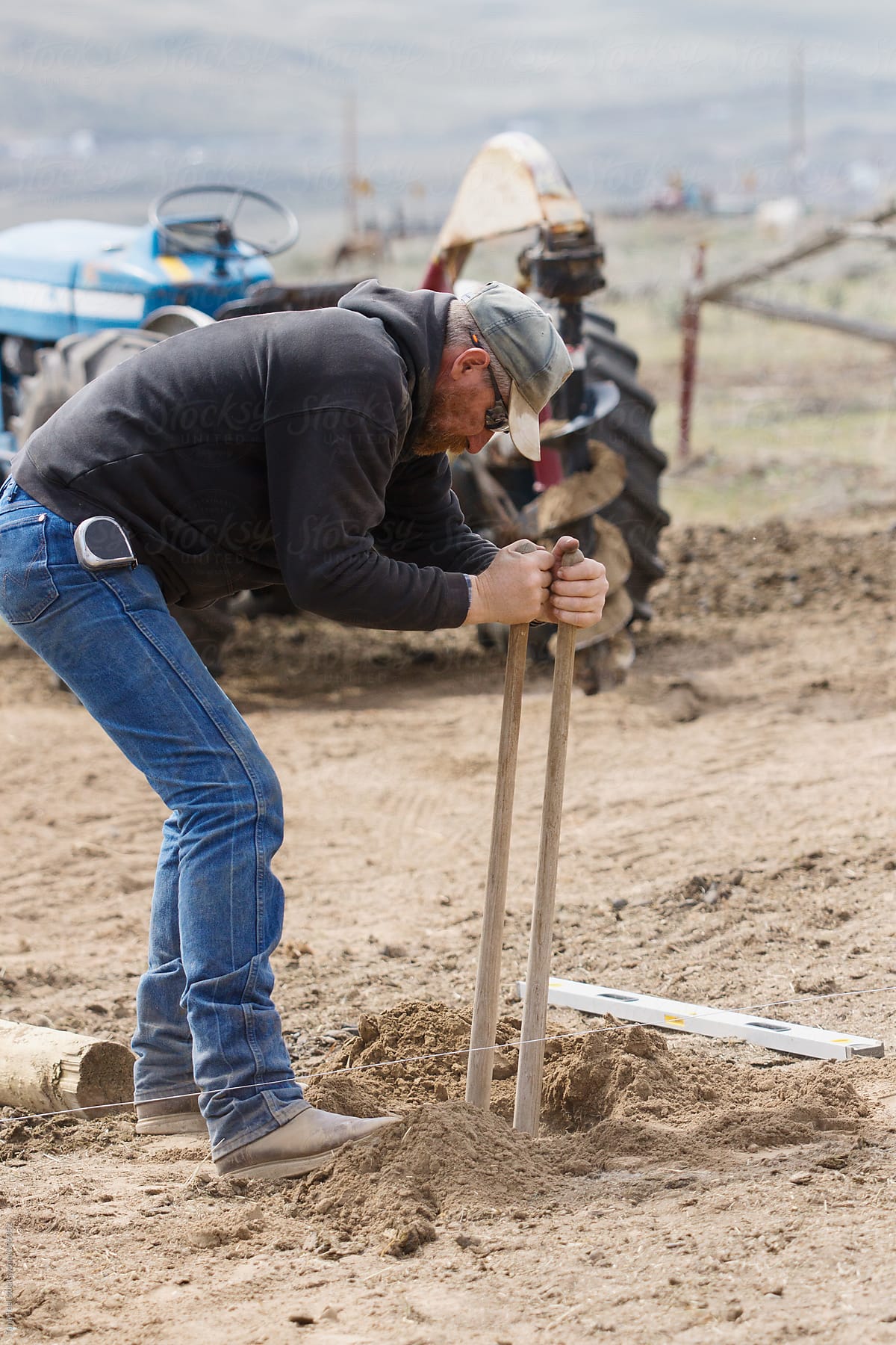 A man using a post hole digger