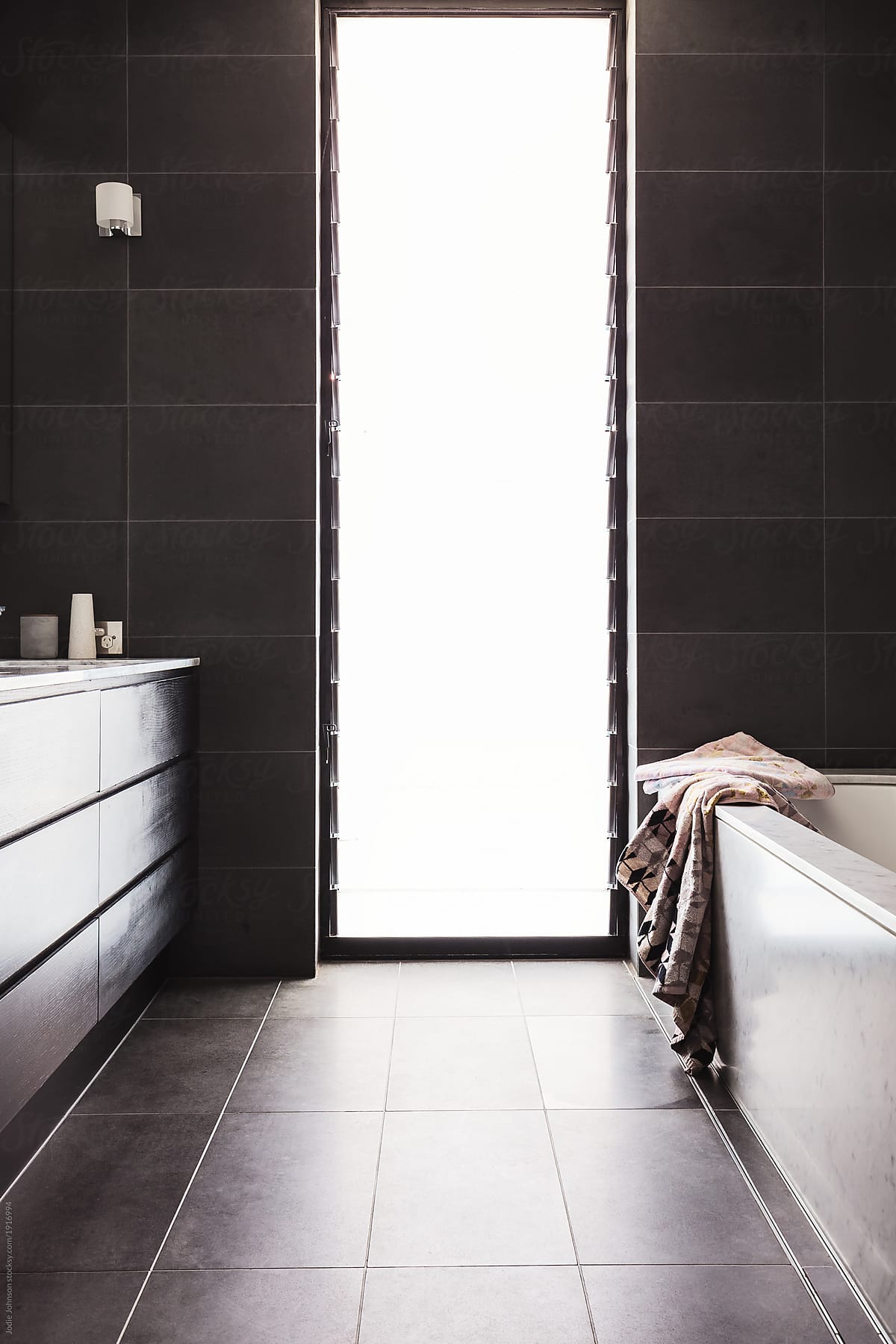 Luxury Dark Tiled Bathroom With Floor To Ceiling Louvre Window By