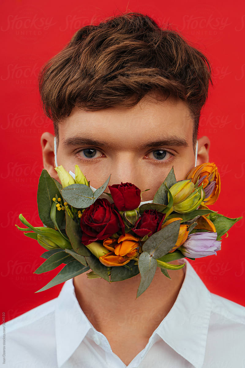 attractive young man in a flower mask on a red background
