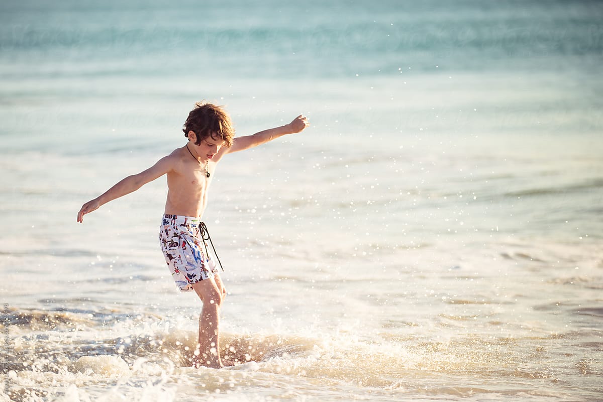 Child having fun with a skim board at the beach at sunset