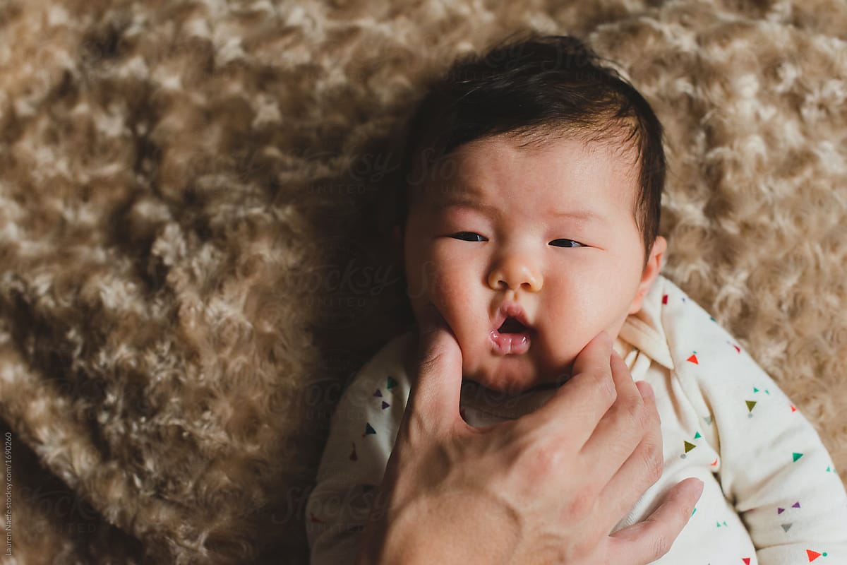 Dad's Hand Pinching Baby's Cheeks by Lauren Lee