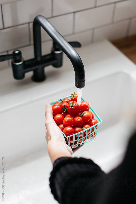 tomatoes being washed in a white sink