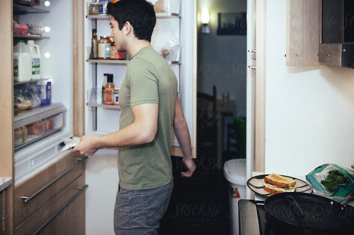Mexican-American Young Male Student Looking inside Fridge Preparing Breakfast Sandwich