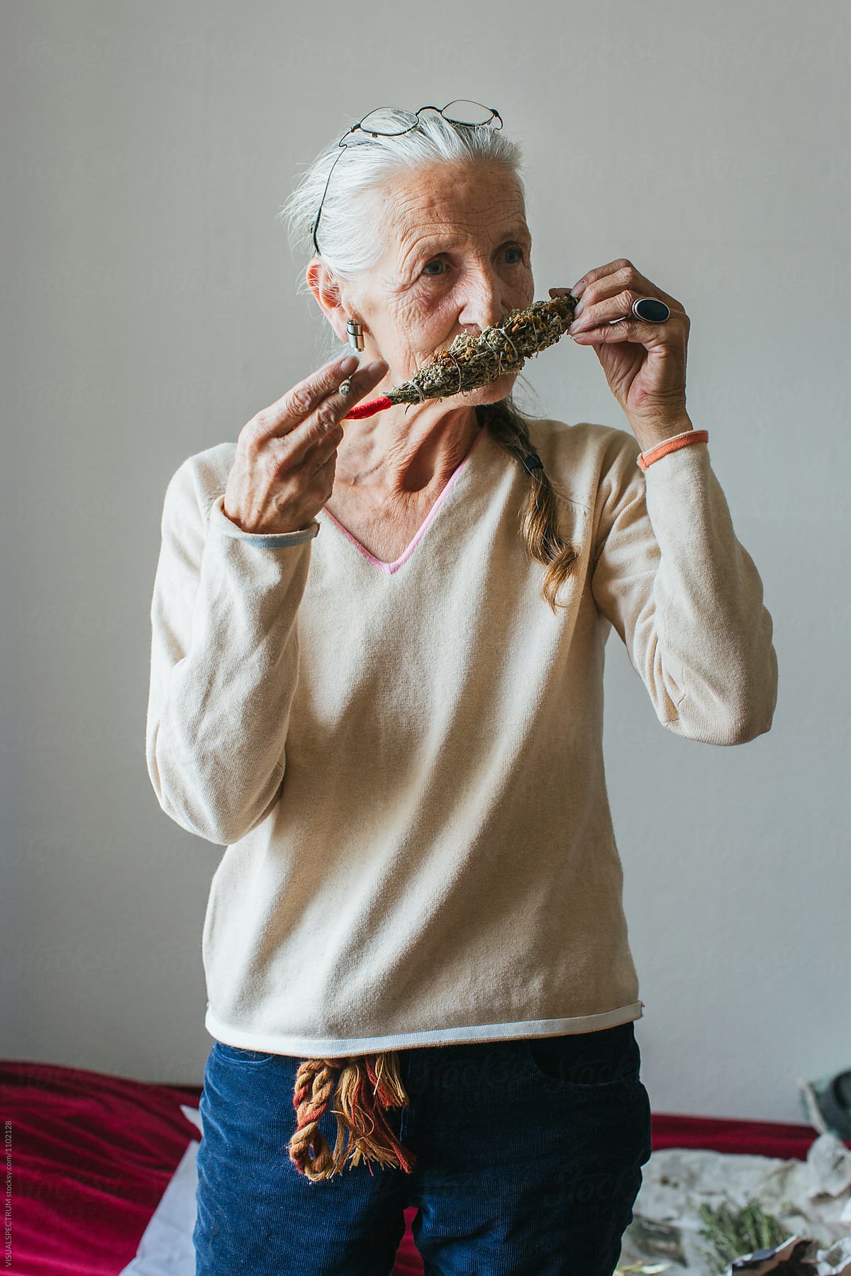 Environmental Portrait of Senior Smoking Woman with Grey Hair Smelling Smudge Stick