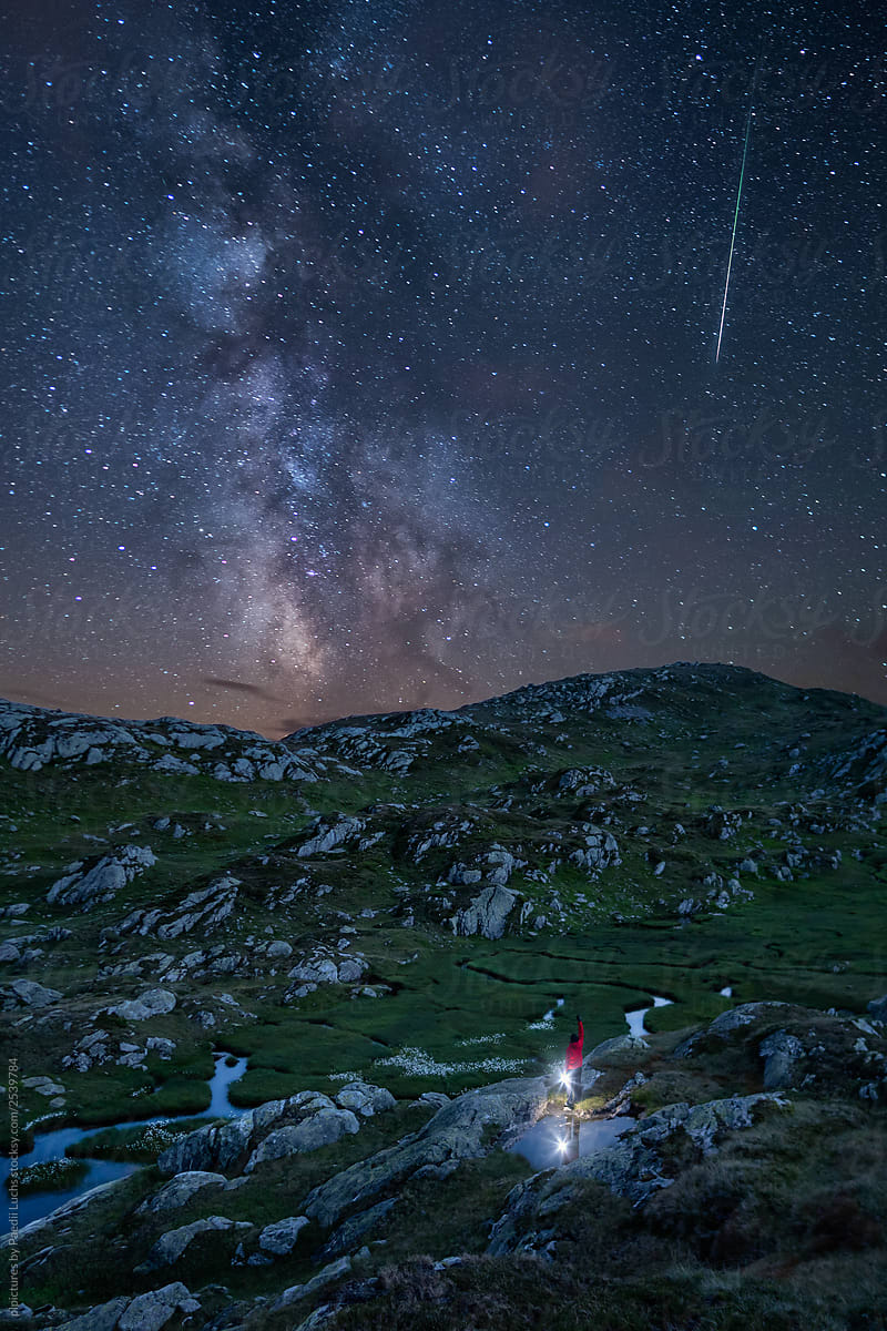 Man holding lantern standing under a starry sky