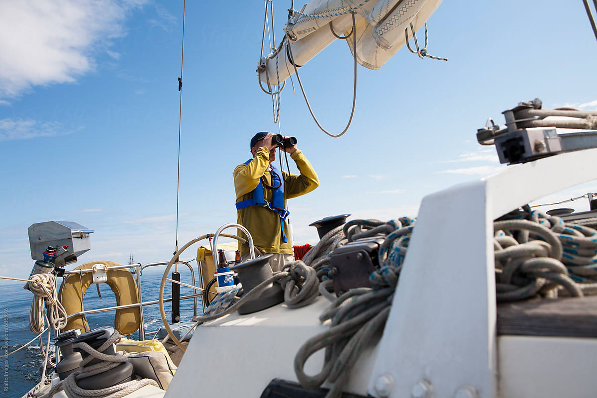 Man on sailboat, looking through binoculars