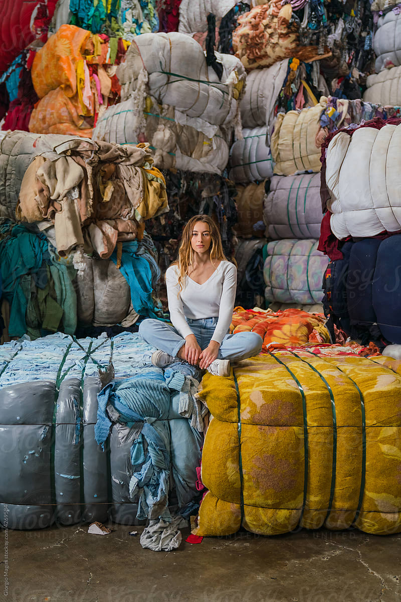 Pretty Woman Sitting in a Clothes Recycling Warehouse