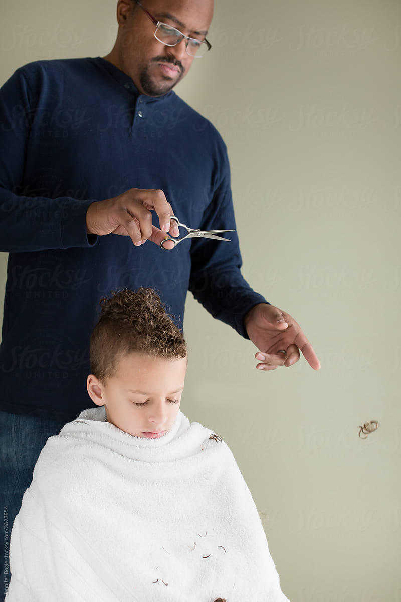 Father crops curls as he trims son\'s hair at home