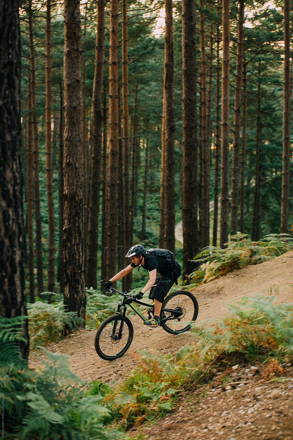 A man cycling fast down a sandy slope in a forest