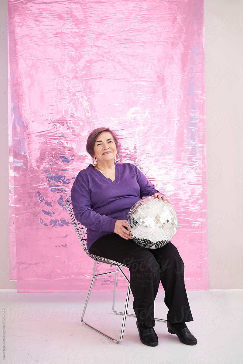 Smiling senior woman sitting in studio with disco ball