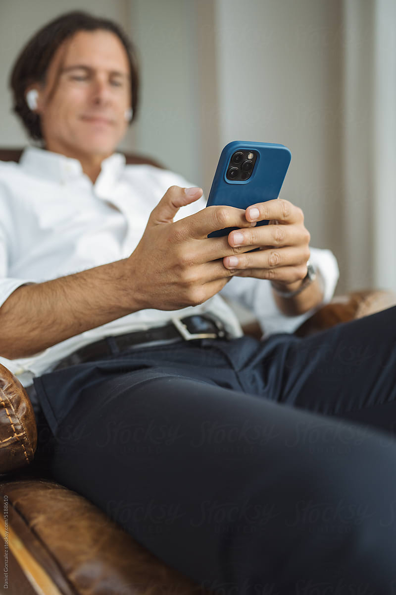 Man resting on chair and using smartphone