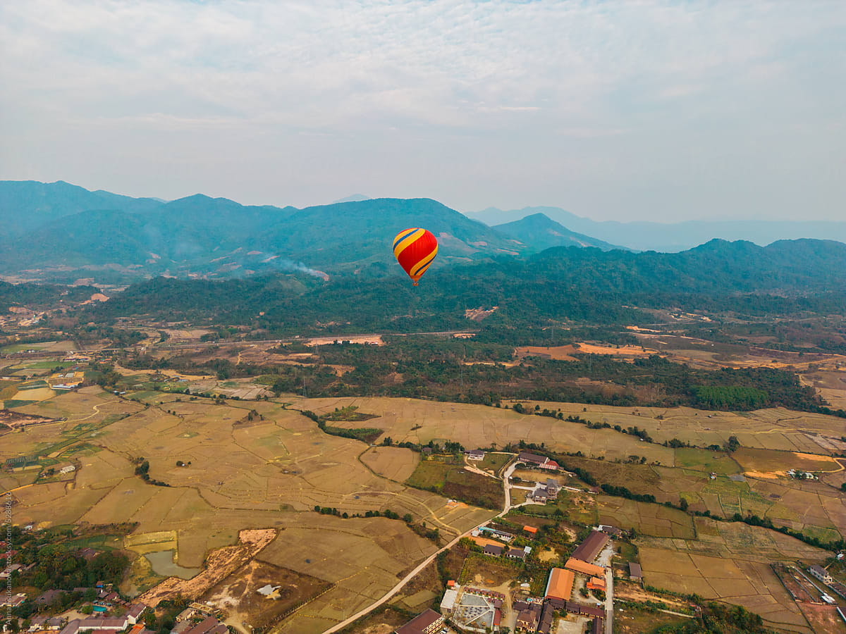 Aerial view of red hot air balloon above rice fields in Laos