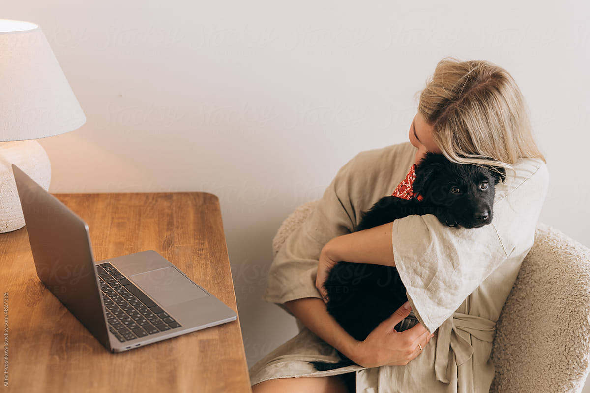 Content lady hugging dog at desk with netbook