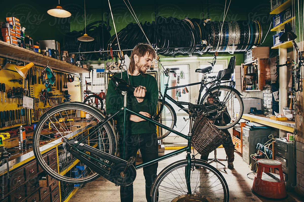 Young mechanic suspending a bicycle in a workshop