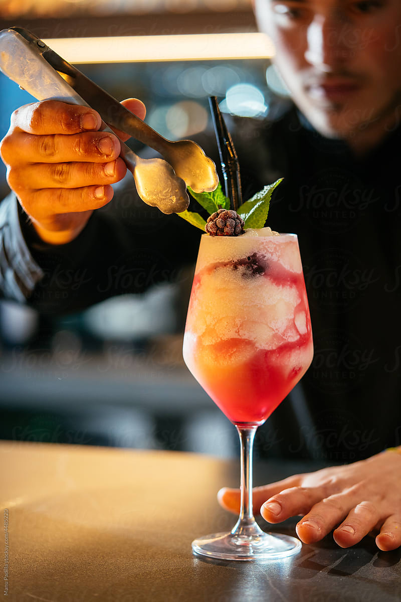 Bartender adding berry on top of cold cocktail