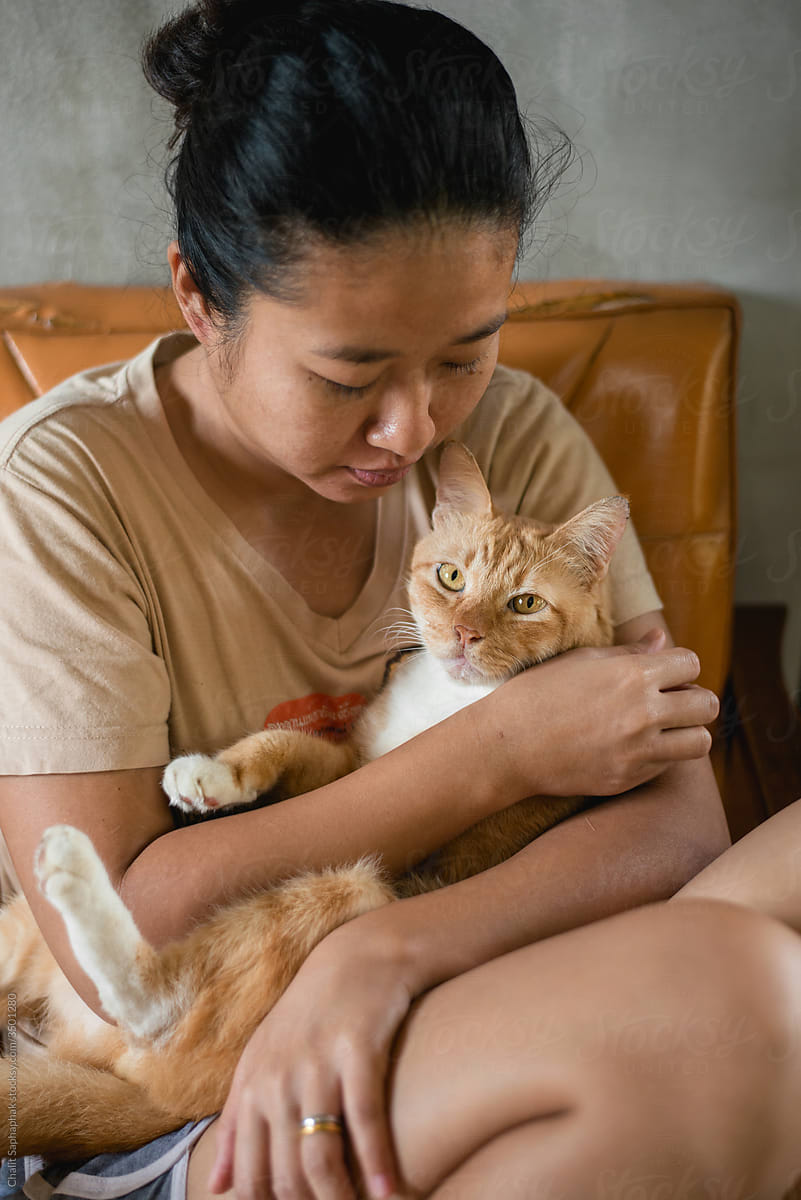 Asian woman hugging orange cat