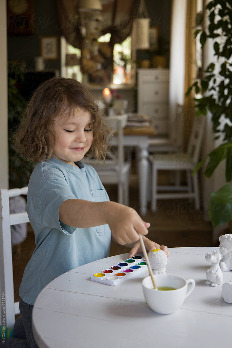 Adorable boy paints figurines at home