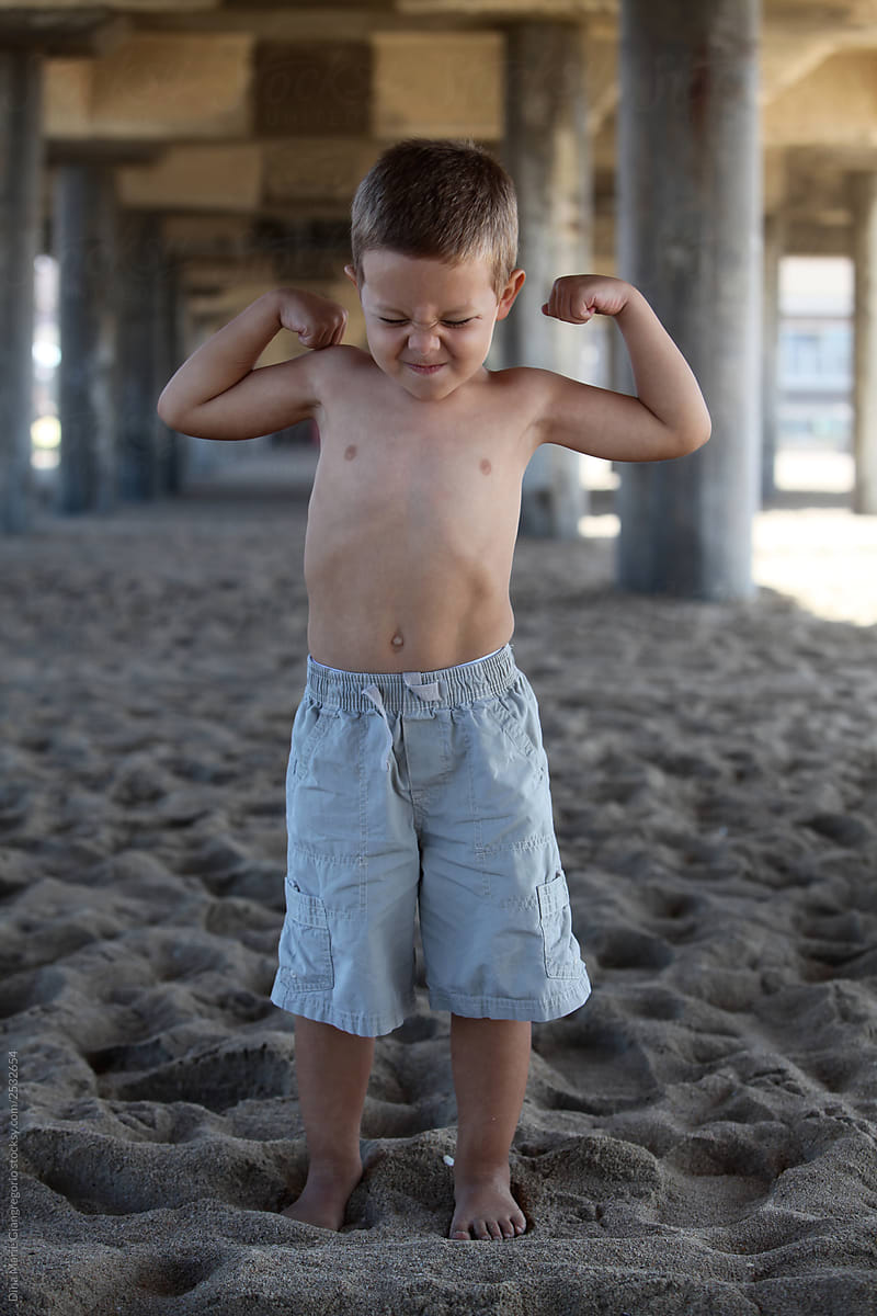 Little Boy Flexing his Muscles on the Beach