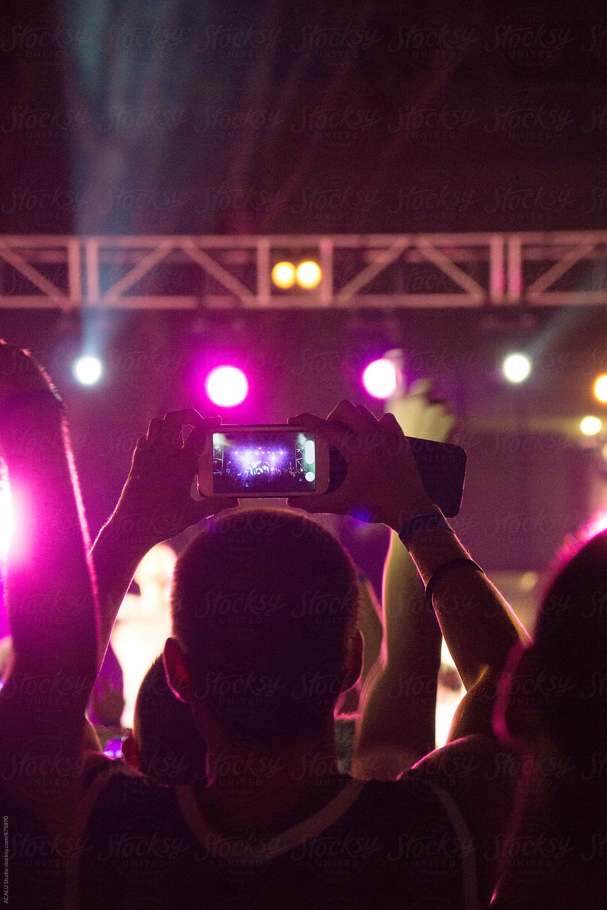 Person taking a picture with your smartphone at a concert in the evening