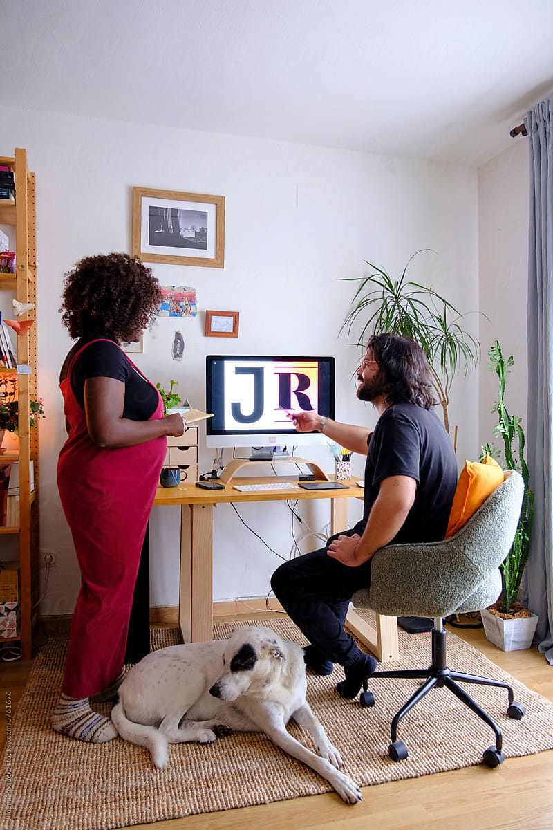 Pregnant woman and man working in home studio with dog