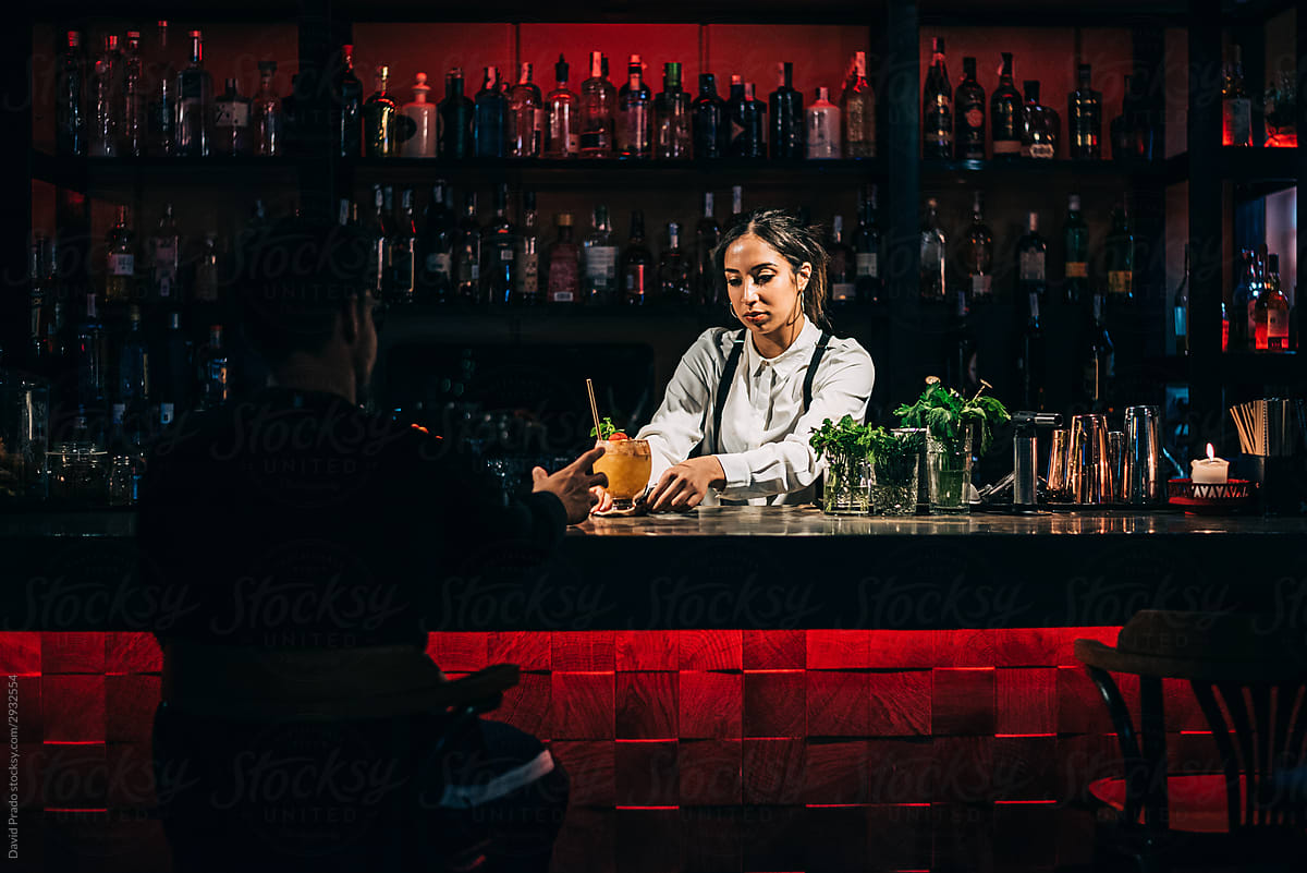 Female barkeeper serving cocktail to anonymous customer